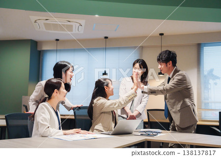 一位女士欣喜若狂,在辦公室與其他人擊掌慶祝。 一位女士欣喜若狂,在辦公室與其他人擊掌慶祝。 138137817