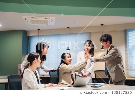 一位女士欣喜若狂,在辦公室與其他人擊掌慶祝。 一位女士欣喜若狂,在辦公室與其他人擊掌慶祝。 138137820