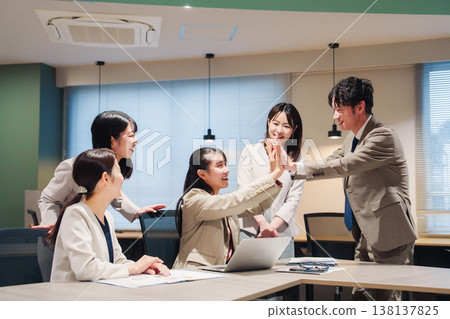 A woman is overjoyed and high-fiving others in the office. A woman is overjoyed and high-fiving others in the office. 138137825