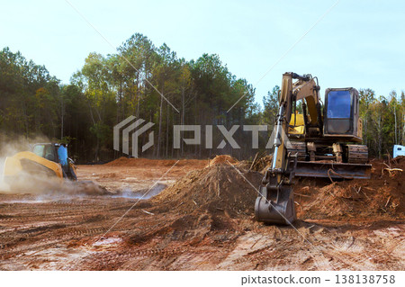 Two pieces of heavy equipment are clearing land in dirt prepare area for upcoming projects. 138138758