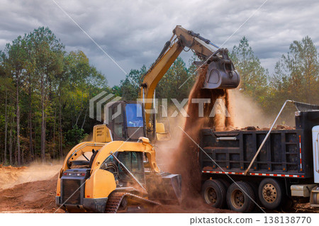 Heavy machinery digs transfers soil to dump truck at construction site at ground leveling 138138770