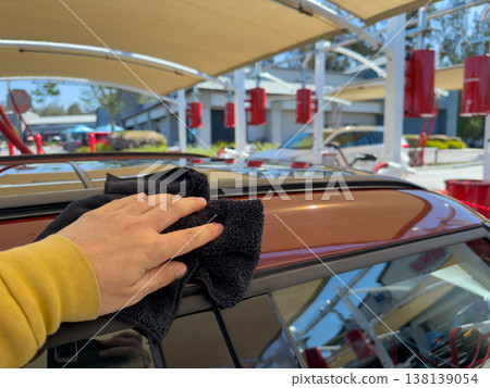Man wiping and drying car with grey microfiber rag outdoors, closeup 138139054