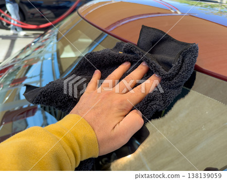 Man wiping and drying car with grey microfiber rag outdoors, closeup Man wiping and drying car with grey microfiber rag outdoors, closeup 138139059
