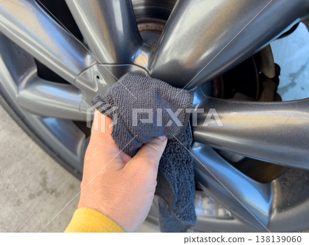 Man wiping and drying car with grey microfiber rag outdoors, closeup 138139060