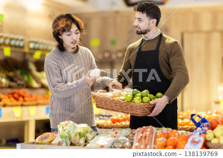 Seller offers daikon to young woman customer 138139769