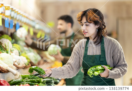 Seller in grocery vegetable shop arrange pepper. 138139774