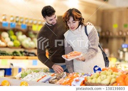 Married couple choose ripe carrot together at grocery supermarket Married couple choose ripe carrot together at grocery supermarket 138139803