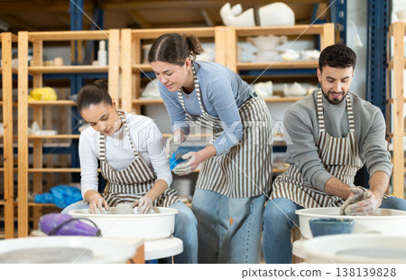 Woman help girl sculpting ceramic product from raw clay on pottery wheel in workshop Woman help girl sculpting ceramic product from raw clay on pottery wheel in workshop 138139828