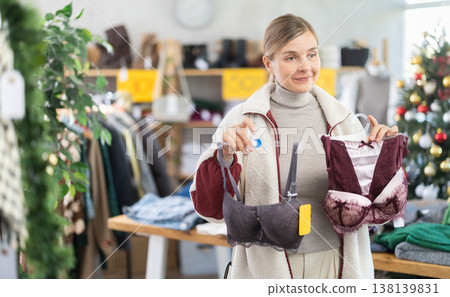 Positive young woman choosing bra in clothing store 138139831