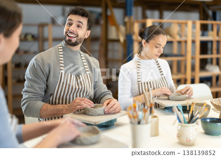 Three pottery workshop workers sculpt from raw clay 138139852
