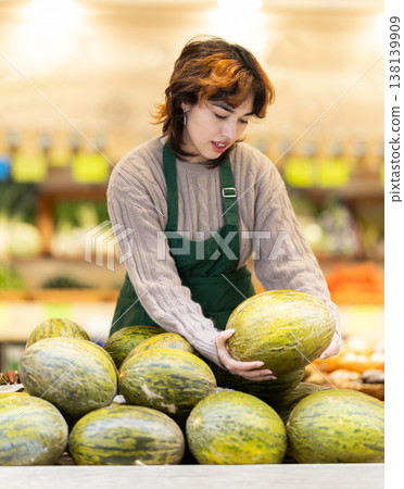 Seller in grocery vegetable shop arrange melon. 138139909