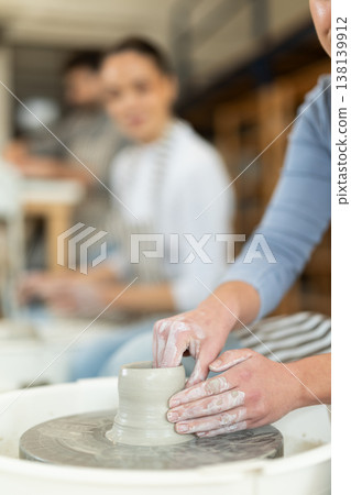 Closeup of female hands sculpting at a table in pottery wheel studio Closeup of female hands sculpting at a table in pottery wheel studio 138139912