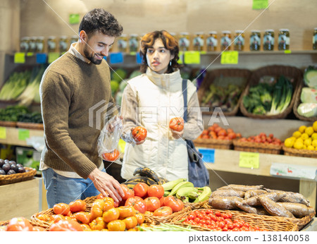 Young couple choose tomatoes in store in store Young couple choose tomatoes in store in store 138140058