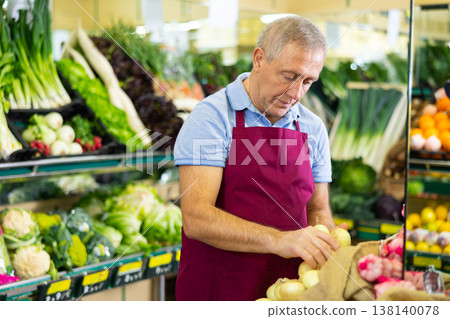 Professional old male seller putting onion on shelves in grocery shop Professional old male seller putting onion on shelves in grocery shop 138140078