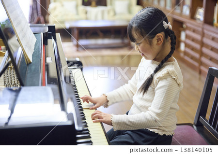 A girl practicing the grand piano at a music stand. A girl practicing the grand piano at a music stand. 138140105