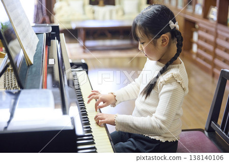 A Japanese girl playing the piano in a piano lesson. A Japanese girl playing the piano in a piano lesson. 138140106