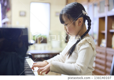 A girl playing the piano with good posture in her piano lesson. A girl playing the piano with good posture in her piano lesson. 138140107