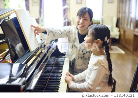 A teacher and a female student giving a piano lesson at a piano studio. A teacher and a female student giving a piano lesson at a piano studio. 138140121
