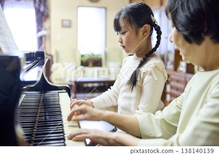 一個女孩一邊練習鋼琴,一邊聽老師演奏。 一個女孩一邊練習鋼琴,一邊聽老師演奏。 138140139
