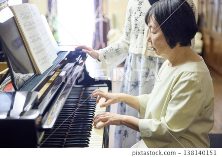 一位精神矍鑠的老年婦女正在學習鋼琴。 138140151