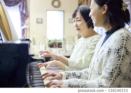 一位活力充沛的老年婦女在鋼琴課上與她的老師一起演奏鋼琴二重奏。 一位活力充沛的老年婦女在鋼琴課上與她的老師一起演奏鋼琴二重奏。 138140153