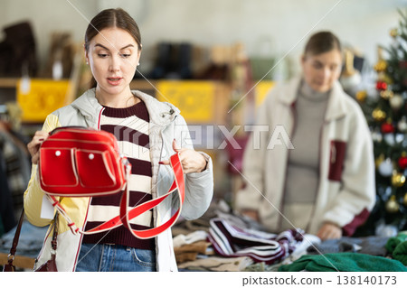 Woman client looks at products in store, choose closely ladys bag Woman client looks at products in store, choose closely ladys bag 138140173