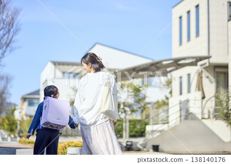 一位母親牽著女兒的手走在住宅區裡，時時留意著她。 138140176