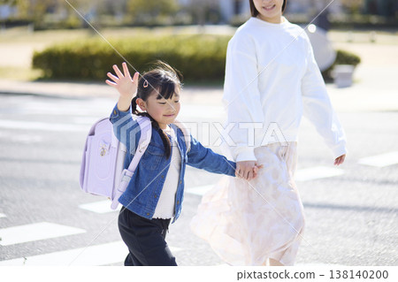背著書包的小學生們舉著一隻手走過行人穿越道。 背著書包的小學生們舉著一隻手走過行人穿越道。 138140200