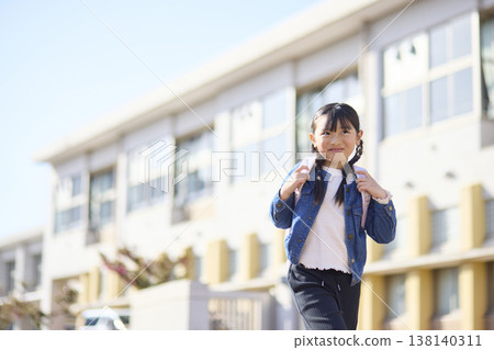 一個背著書包的小學生小女孩放學回家。 一個背著書包的小學生小女孩放學回家。 138140311