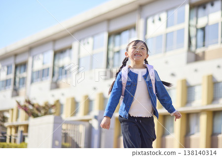 一個背著書包的小學生小女孩放學回家。 一個背著書包的小學生小女孩放學回家。 138140314