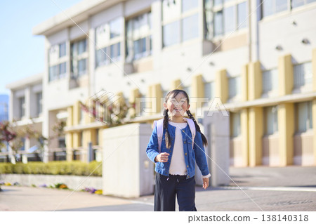 A young elementary school girl with a schoolbag on her back is walking home from school. A young elementary school girl with a schoolbag on her back is walking home from school. 138140318