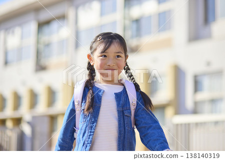 一個背著書包的小學生小女孩放學回家。 一個背著書包的小學生小女孩放學回家。 138140319
