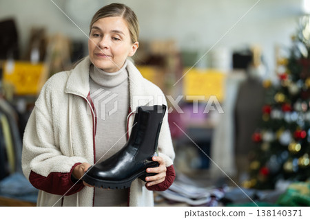 Woman in winter jacket choosing platform boots on Christmas tree background Woman in winter jacket choosing platform boots on Christmas tree background 138140371