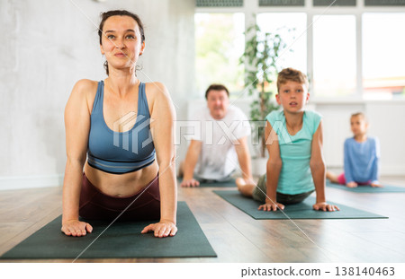 Mom, dad, son and daughter perform pose dog muzzle up - cobra, Urdhva Mukha Shvanasana- Bhujangasana Mom, dad, son and daughter perform pose dog muzzle up - cobra, Urdhva Mukha Shvanasana- Bhujangasana 138140463