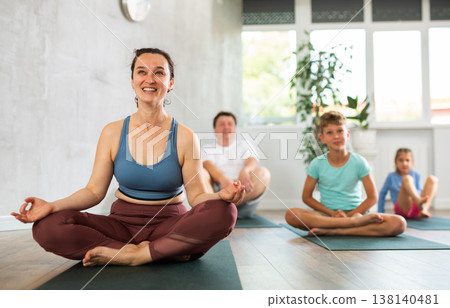 Adult woman with family practicing yoga in studio Adult woman with family practicing yoga in studio 138140481