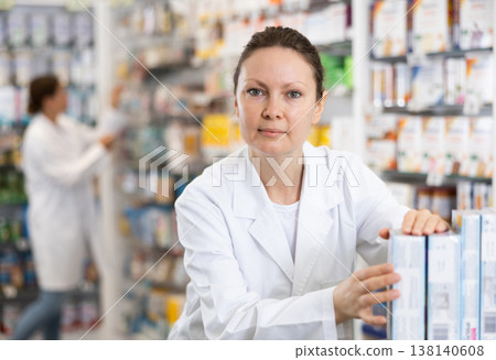 In pharmacy, woman chemist makes out showcase with warming analgesic ointments 138140608