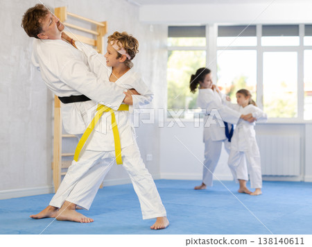 Parent with child athletes in pair conduct training battle in oriental fighting technique Parent with child athletes in pair conduct training battle in oriental fighting technique 138140611