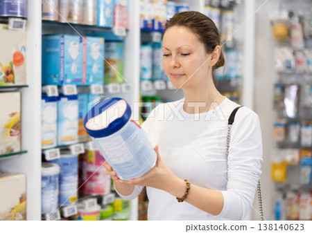 Adult woman chooses baby formula in pharmacy 138140623