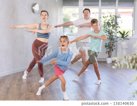 Cute little girl practicing dance movements with her family members 138140630