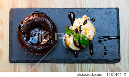 Sweet lava cake served with vanilla ice cream and mint at black plate 138140645