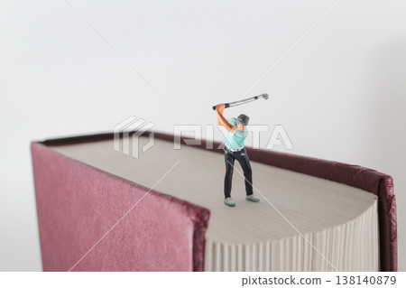 Miniature Golfer Finishes Swing On Oversized Book Surface Miniature Golfer Finishes Swing On Oversized Book Surface 138140879