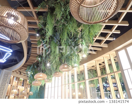 Hanging plants and lighting details create a warm and inviting cafe interior. Hanging plants and lighting details create a warm and inviting cafe interior. 138141574