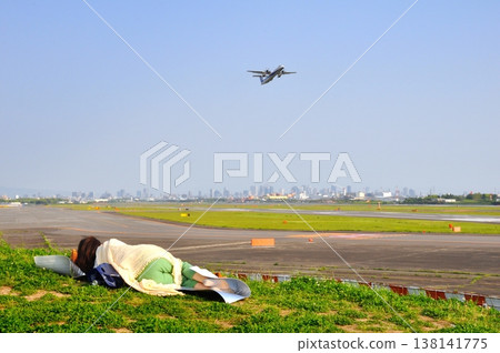 A woman taking a break while watching airplanes. A woman taking a break while watching airplanes. 138141775