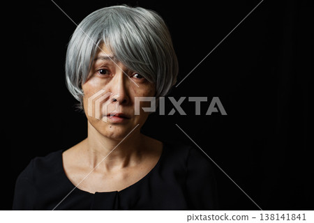 一位面容悲傷、頭髮花白的老婦人，眼中噙滿了淚水。 138141841