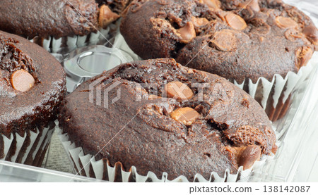 Freshly baked chocolate muffins stacked surface with chocolate chunks beside them Freshly baked chocolate muffins stacked surface with chocolate chunks beside them 138142087