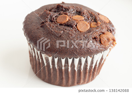 Freshly baked chocolate muffins stacked surface with chocolate chunks beside them on a transparent background 138142088