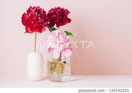 Red peony flower in a vase on a pastel pink background, copy space 138142203