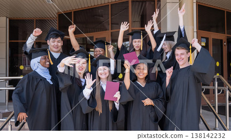 Happy students of different nationalities in graduation gowns hold their diplomas. Happy students of different nationalities in graduation gowns hold their diplomas. 138142232