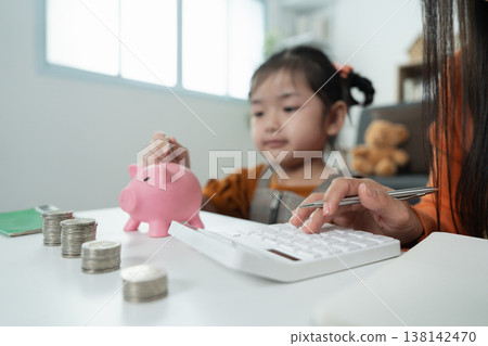 Mother teaching child financial literacy with piggy bank Mother teaching child financial literacy with piggy bank 138142470
