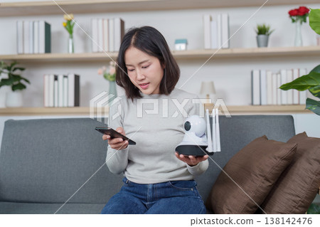 Woman configuring a smart home security camera Woman configuring a smart home security camera 138142476